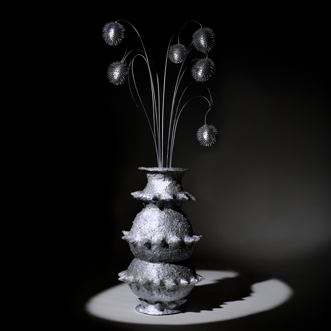 Handbuilt papier-mâché sculptural vessel “Tálä” by Pulp Fictitious with an added metallic floral arrangement, displayed against a dark background.